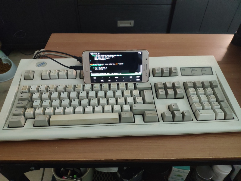Mi teclado clásico IBM de 1985, un Samsung J5 con Lineage OS + el emulador de terminal Termux y un cable OTG, todo conectado por WiFi al servidor.